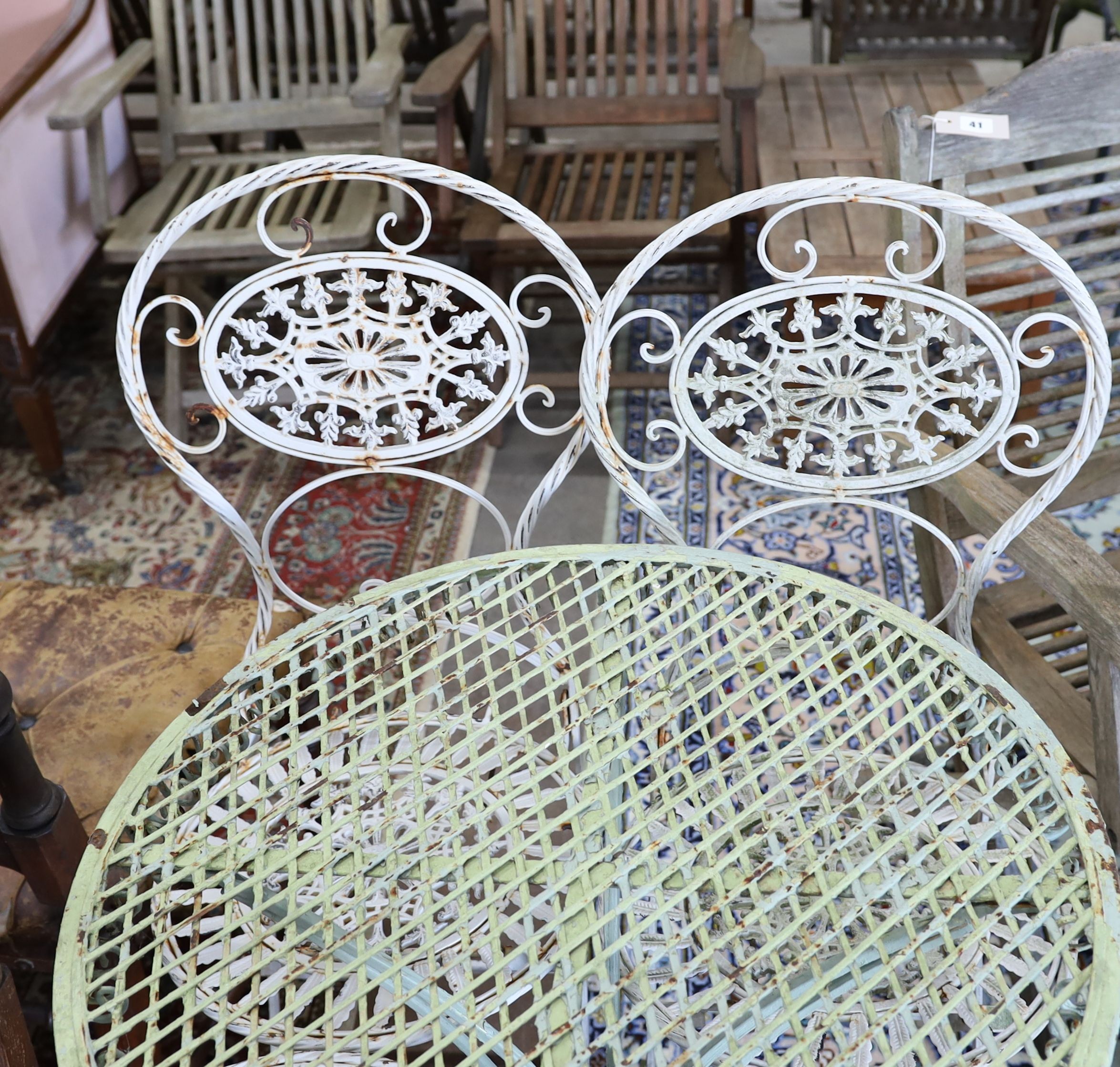 A wrought iron circular garden table, diameter 65cm, height 74cm and four folding chairs